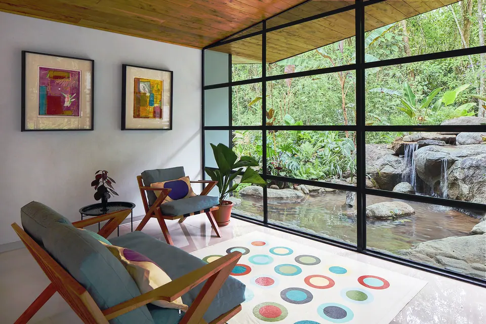 Sala de Cascada Suite con sillas de diseño y rocas del río afuera