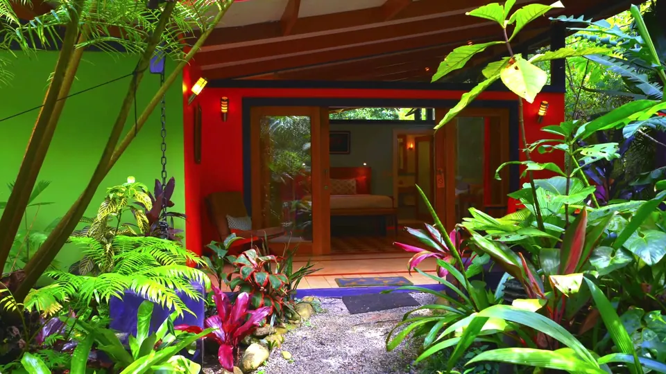Casita Verde con paredes verde lima y puertas rojas entre plantas tropicales