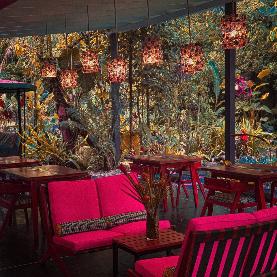 Fucsia restaurant with pink chairs and lanterns among tropical plants