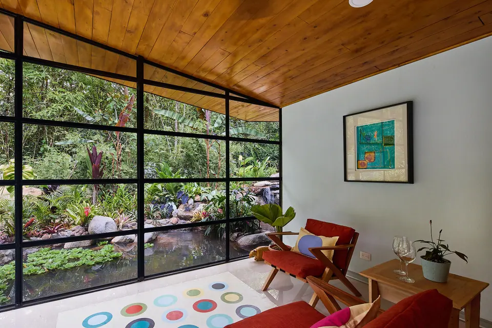 Sala de Laguna Suite con paredes de vidrio y sillón rojo
