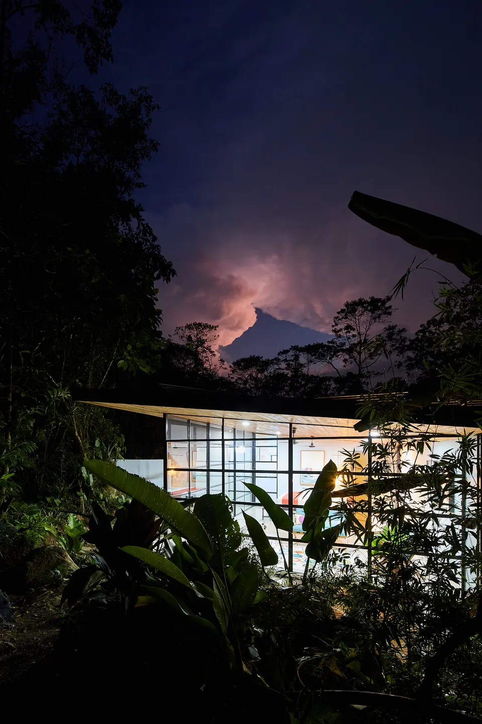 Glass-walled suite at dusk with the mountains behind