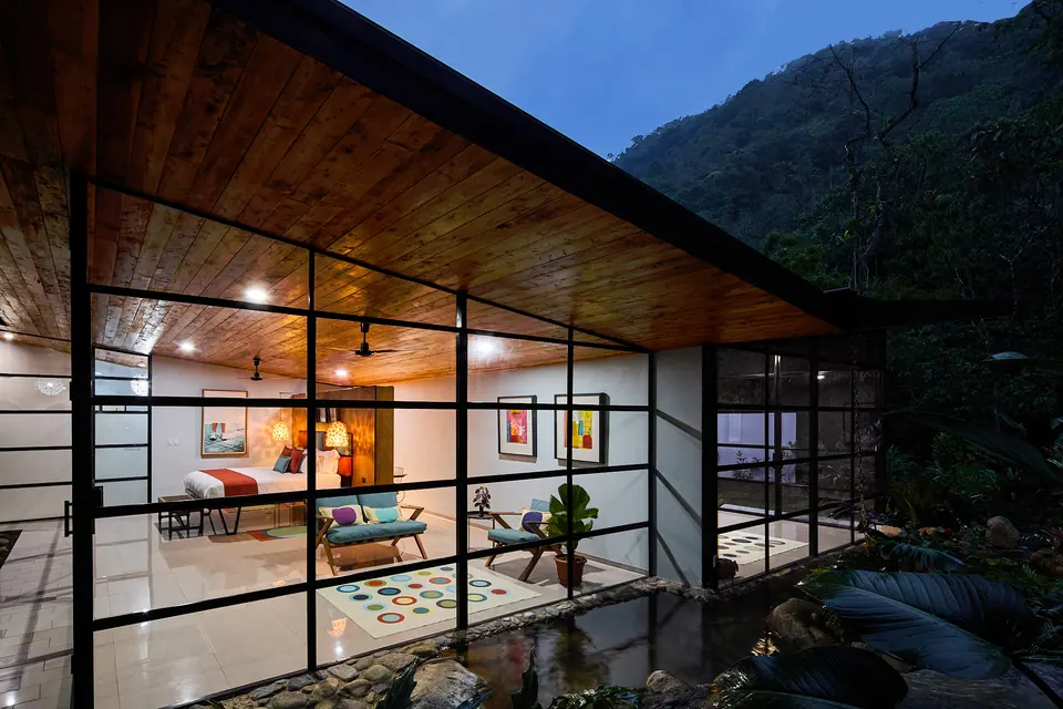 Suites de vidrio iluminadas al anochecer en el bosque