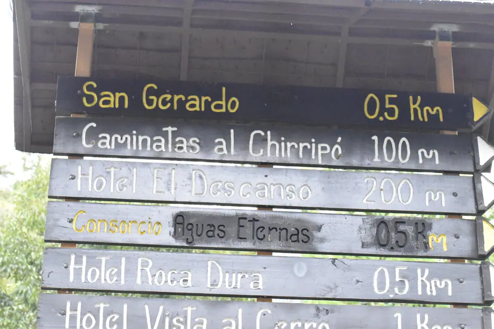 Wooden village signpost in San Gerardo de Rivas pointing to the Chirripó trailhead
